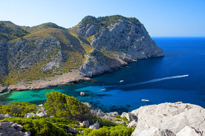 Scenic view of sea and rocks against blue sky