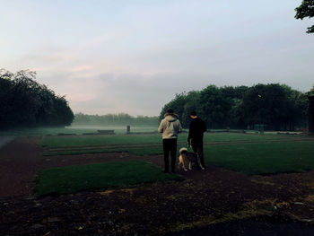 Rear view of couple standing on field against sky