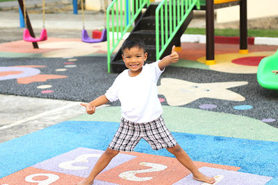 Portrait of smiling boy showing thumbs ups in playground