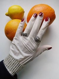 High angle view of hand holding orange over white background