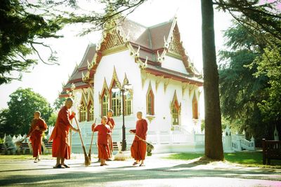 People walking outside temple against building