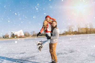 Portrait of smiling couple standing on frozen lake against sky