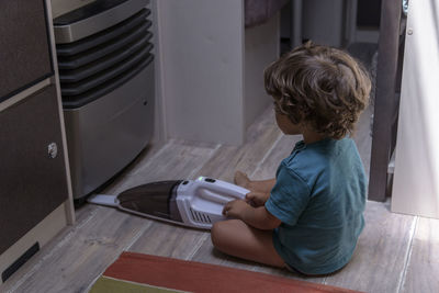 A sweet little boy vacuums the caravan while on vacation. a cute boy is cleaning the caravan.
