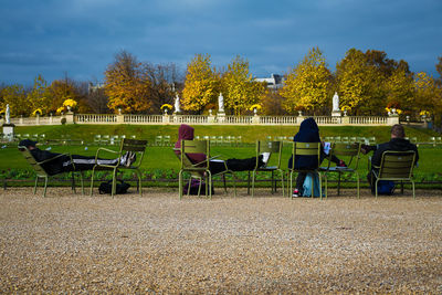 Rear view of people walking in park against sky