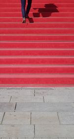 Low section of woman walking on red umbrella