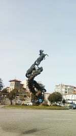 Statue in city against clear sky