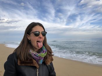 Young woman wearing sunglasses on beach against sky