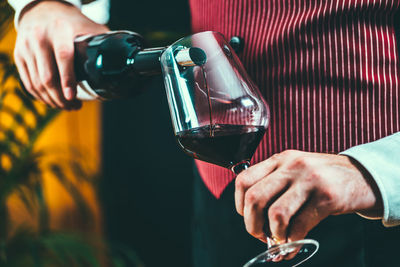 Midsection of man pouring wine in wineglass