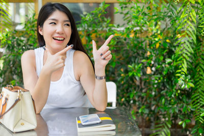 Cheerful young woman gesturing while sitting by plants