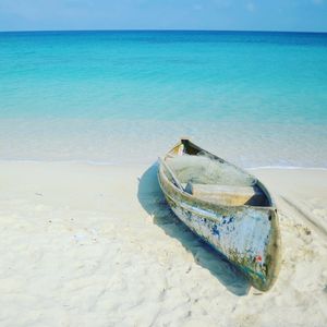 Abandoned boat moored on beach against sky