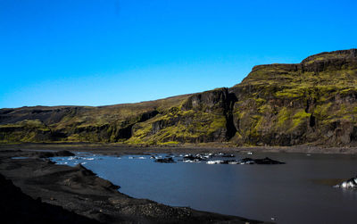Boats in calm sea against clear blue sky