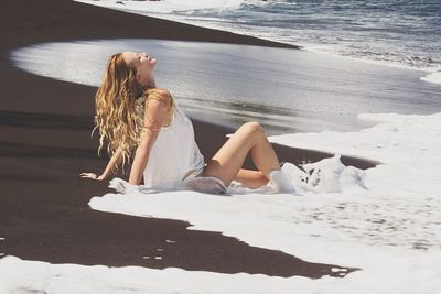 Side view of woman relaxing on shore at beach