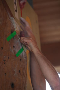 Cropped hands of man holding grips on wooden wall