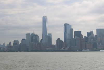 Sea by modern buildings against sky in city