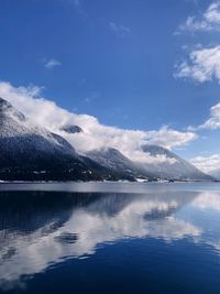 Scenic view of lake by mountains against blue sky