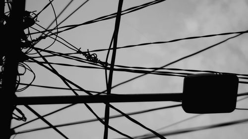 Low angle view of silhouette cables against sky