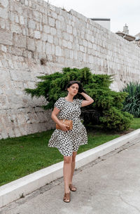 Full length of woman standing against wall