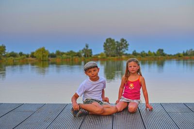 Children sitting on pier. siblings. two children of different age - elementary age boy and preschool