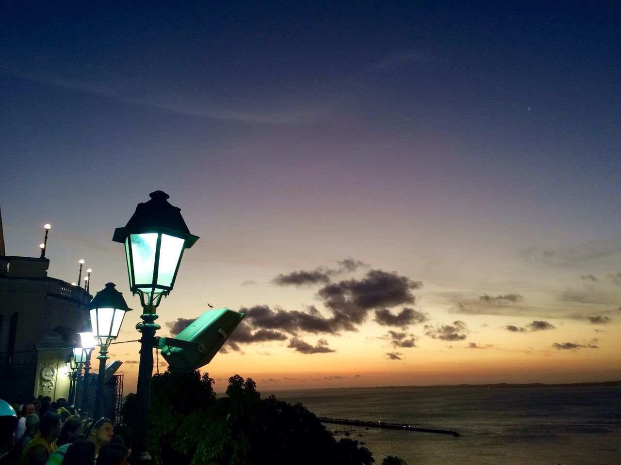 sea, horizon over water, sunset, silhouette, sky, scenics, beauty in nature, water, tranquility, beach, nature, tranquil scene, street light, orange color, lighting equipment, cloud, idyllic, cloud - sky, dusk, blue