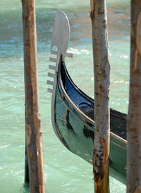 Close-up of a fragment of a gondola in the venice canal in italy, anchored to wooden poles. 