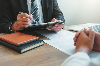 Midsection of man reading book on table