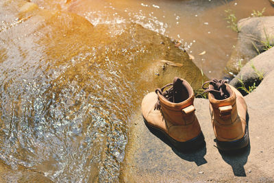 High angle view of shoes on rock over river