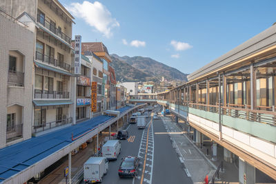 Cars on road by buildings against sky in city