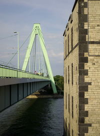 Bridge over river by buildings against sky