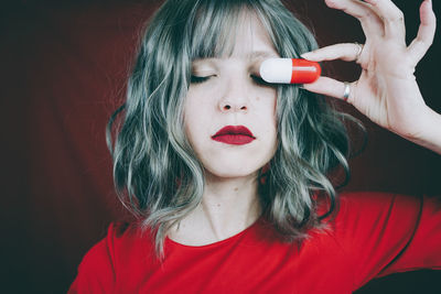 Woman covering eye with capsule