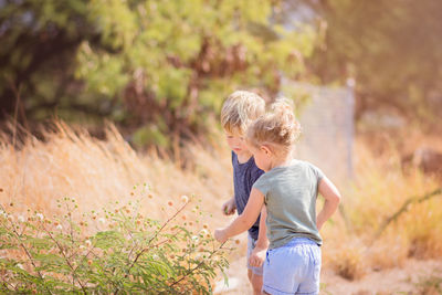 Boy standing by tree against plants