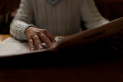 Midsection of person reading book in home