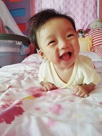 Close-up of cute happy baby girl lying on bed at home