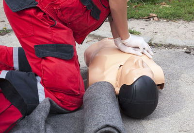 Midsection of paramedic performing cpr on mannequin