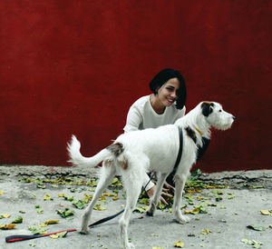 Portrait of woman with dog against red wall