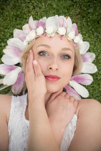 Portrait of beautiful woman wearing flower tiara lying on grass