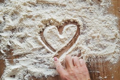 Close-up of hand holding heart shape on sand