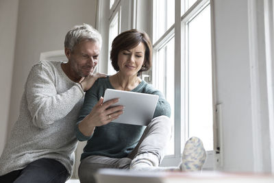 Couple sharing tablet at the window