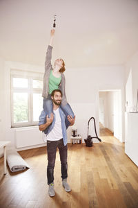 Full length of happy friends standing on floor at home