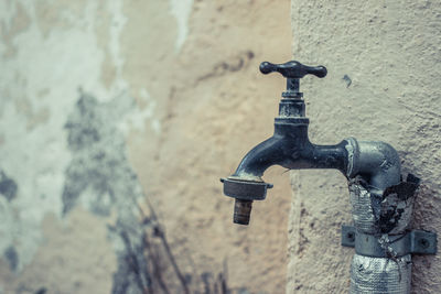 Close-up of old faucet against wall