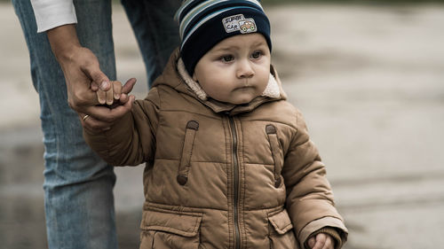 Midsection of woman holding baby boy hand