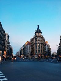 City street by buildings against blue sky