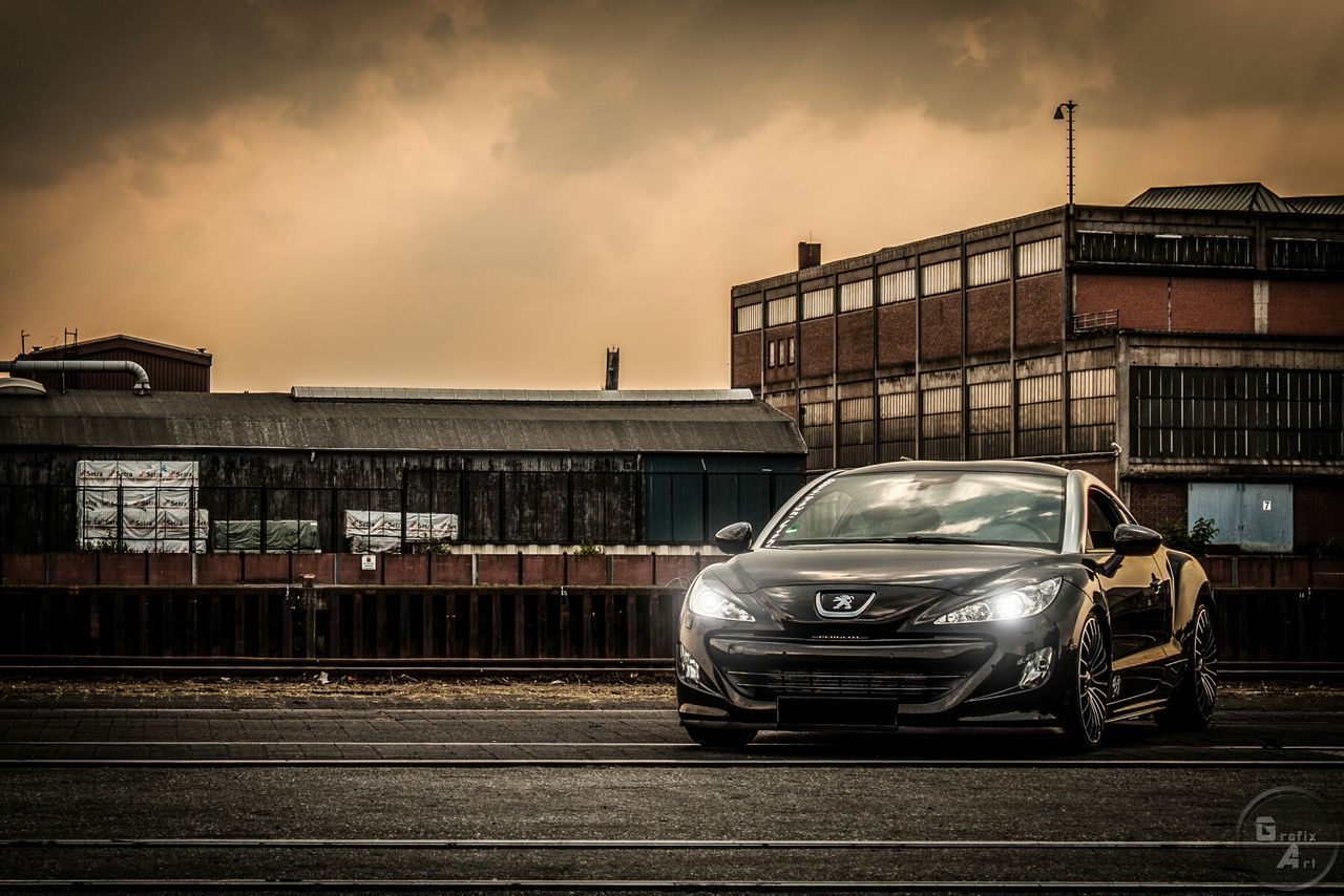 transportation, sky, mode of transport, public transportation, railroad track, building exterior, rail transportation, train - vehicle, text, land vehicle, cloud - sky, architecture, western script, built structure, railroad station, communication, car, city, railroad station platform, cloudy