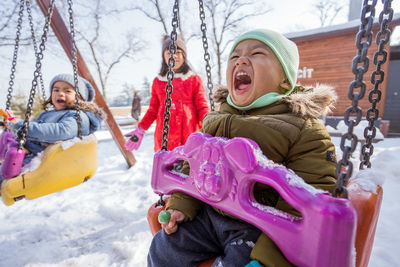 Portrait of smiling boy swinging at playground