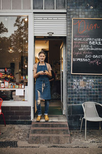 Portrait of male owner standing at entrance of deli