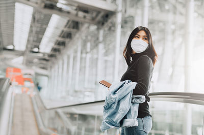 Woman looking away while standing at railroad station