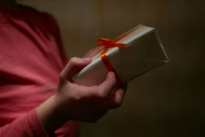 Close-up of girl holding gift against wall