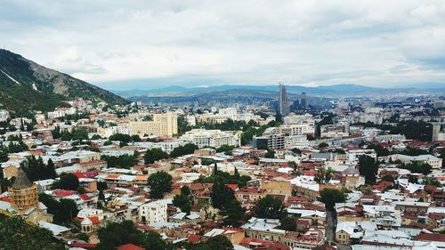 Aerial view of cityscape against cloudy sky