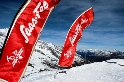 Information sign on snowcapped mountain against sky