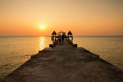 Pier on sea at sunset