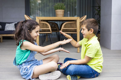 Side view of siblings sitting outdoors